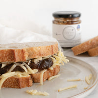 a cheese and onion sandwich sits in front of a jar of the cornish larder caramelised onion chutney.