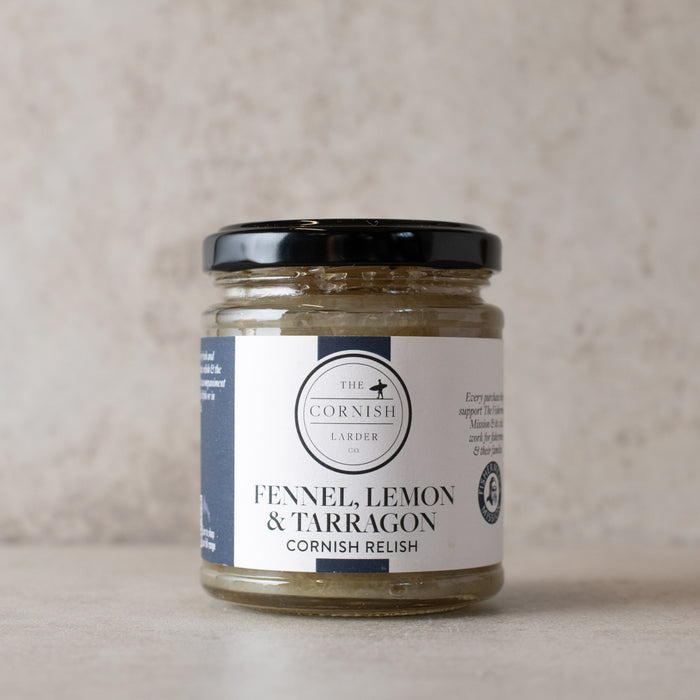 A glass jar of Fennel Relish by The Cornish Larder, featuring a black lid and a white label with navy blue accents, set against a neutral textured beige background.