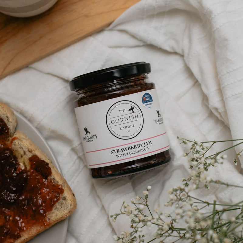 jar of strawberry jam alongside toast and some flowers